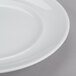 An Arcoroc Rondo white porcelain brunch plate with a rim on a gray surface.