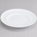 An Arcoroc white porcelain bread and butter plate with a rim on a gray background.