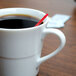 A white Arcoroc coffee cup with a red straw in it.