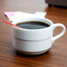 An Arcoroc coffee cup filled with coffee and a red straw.