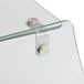 A close-up of a curved glass sneeze guard shelf with metal handles and a metal latch.