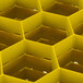 A yellow Vollrath Traex rack with hexagonal compartments.