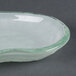 A close-up of an opal glass elliptical bowl with a green rim.