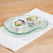A sushi roll on a 10 Strawberry Street Izabel Lam opal glass eliptical dish on a white napkin.