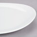A close-up of a 10 Strawberry Street white porcelain oval plate with a curved edge.