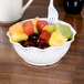 A white plastic swirl bowl filled with fruit.