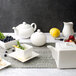 A table set with a white 10 Strawberry Street tea set including a white porcelain covered sugar bowl.