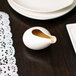 A white porcelain gravy tid bit on a table.