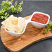 A white porcelain divided bowl with chips and salsa on a wooden board.