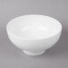 A white Whittier ribbed porcelain bowl with a handle on a gray surface.