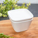 A white square container with a lid on a wooden surface.