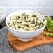 A 10 Strawberry Street Whittier white porcelain ribbed bowl filled with pasta with spinach and cheese on a wooden board.