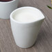 A 10 Strawberry Street Whittier white porcelain milk cup filled with liquid on a white background.