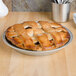 A pie in a Vollrath anodized aluminum pie pan with a lattice top on a table.