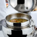 A Vollrath stainless steel round soup chafer with soup inside.