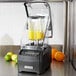 A Hamilton Beach high performance blender with yellow liquid and lemons, limes, and oranges on top.