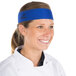 A woman wearing a royal blue Headsweats headband in a professional kitchen.