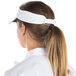 A woman wearing a white Headsweats visor with a ponytail.