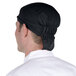 A man wearing a black Headsweats shorty chef cap.