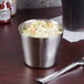 An American Metalcraft stainless steel sauce cup with coleslaw and a fork on a table.
