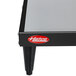 A black and silver Hatco heated shelf on a table with a red logo.