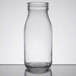 An American Metalcraft glass milk bottle with a lid on a table.