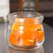 An American Metalcraft condiment mason jar filled with orange slices on a counter.