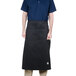 A man wearing a black Chef Revival bistro apron with 2 pockets.