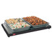 A Hatco portable heated shelf with trays of chicken wings, pasta, and vegetables on a table.