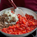 A bowl of food with meat and onions cooked in Furmano's Petite Diced Tomatoes with a spatula.