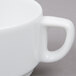 A close-up of an Arcoroc white porcelain stackable cup with a handle.