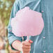 A man holding a pink cotton candy made with Great Western Strawberry Cotton Candy Floss Sugar.