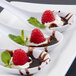 A group of Thunder Group white melamine Chinese wonton soup spoons with chocolate and raspberry dessert on them.