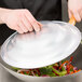 A person using a Thunder Group aluminum wok cover to cook vegetables in a wok.