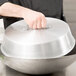 A hand holding a Town aluminum wok cover over a bowl.