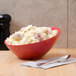 A red GET Diamond Harvest slanted melamine bowl filled with mashed potatoes on a table.