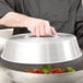 A person holding a Town aluminum wok lid over a bowl of food.