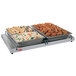 A Hatco portable heated shelf with trays of food on a table.
