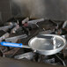 A Vollrath pan cover with a Torogard handle on a pan on a stove.