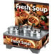 A Vollrath countertop soup merchandiser with bowls of soup and a menu board.