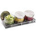A Cal-Mil stainless steel horizontal display with three glass containers of limes.