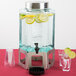 A Cal-Mil stainless steel beverage dispenser with lemons and limes inside.