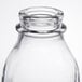 A close up of a Libbey clear glass milk bottle with a lid.