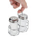 A hand holding an American Metalcraft Spice Mini Shaker Lid over a glass container.