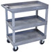 A gray Luxor plastic utility cart with three shelves and wheels.