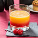 A customizable Arcoroc tumbler filled with orange liquid and two cherries.