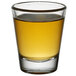 An Arcoroc shot glass with a yellow liquid in it.