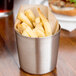 A Tablecraft brushed stainless steel cup filled with French fries.