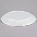 A Tablecraft white round melamine tray with a pebbled rim on a gray surface.