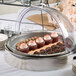 A Tablecraft CaterWare cold server on a table with cupcakes and cookies under a glass dome.